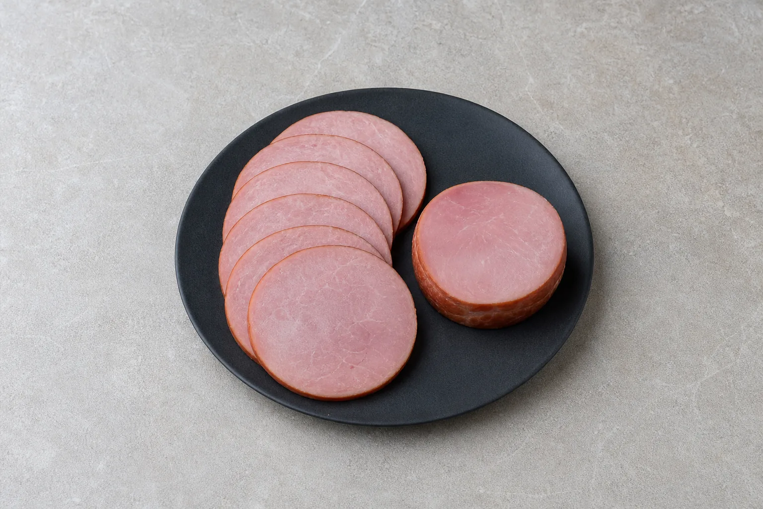 Several round slices of unprepared Canadian bacon with pink centres and browned edges.