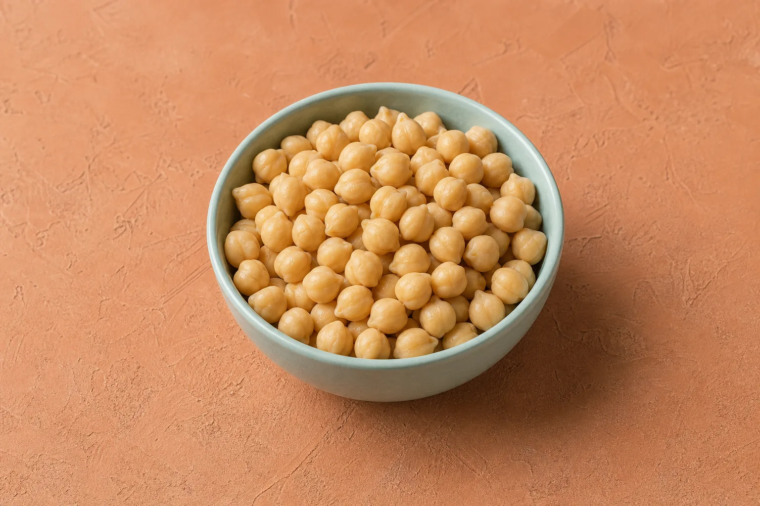 A small bowl of plain cooked beige chickpeas with intact plump shapes and pointed tips.