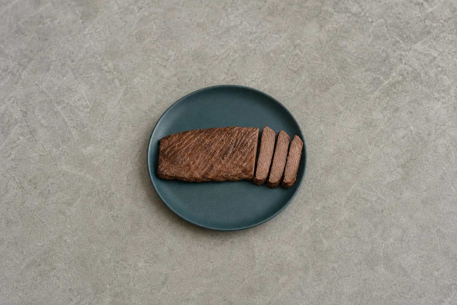 A plain broiled lean skirt steak sliced to show its cooked brown interior.