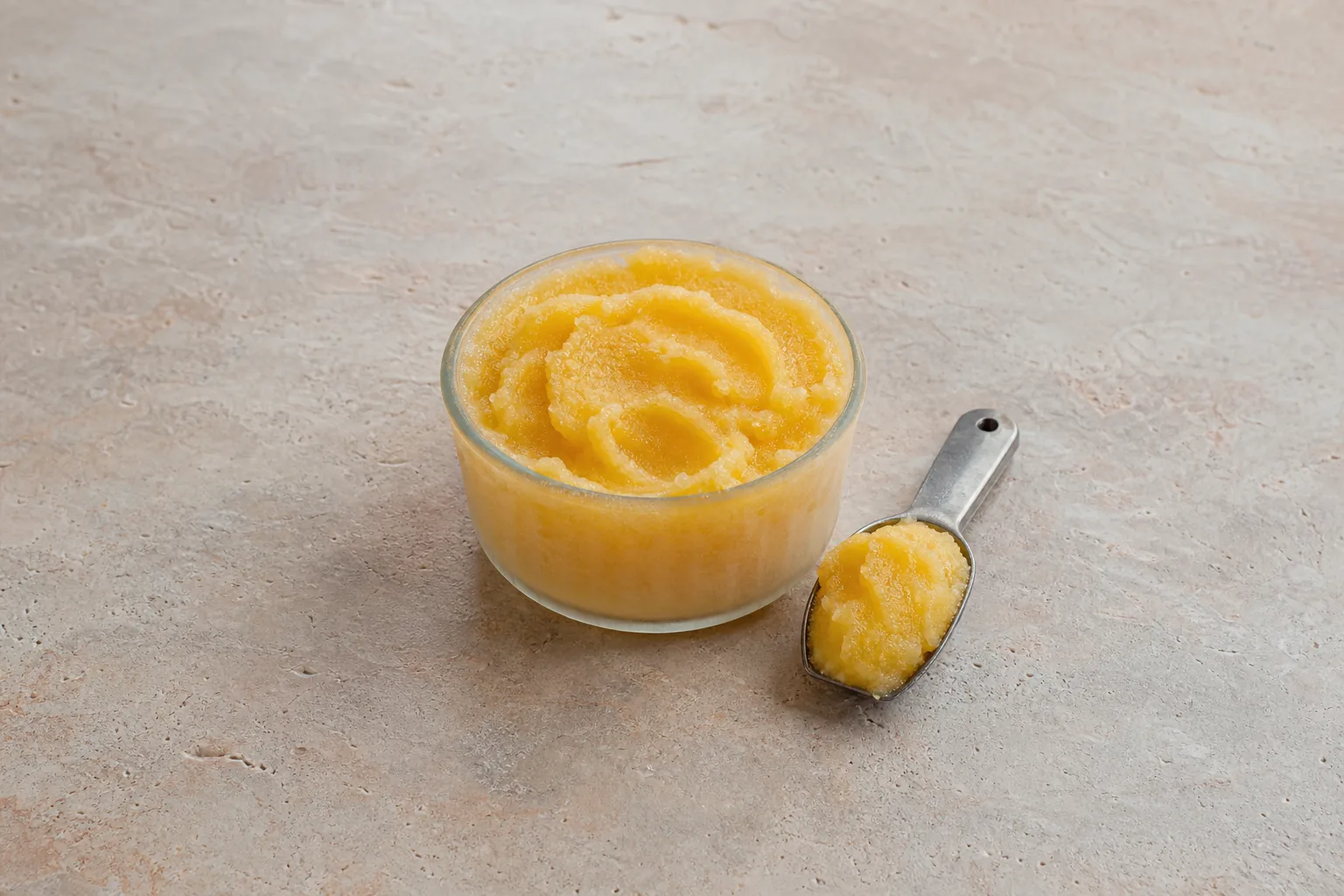 A frosted ramekin of dense golden-yellow frozen juice concentrate with a thick scoopful.