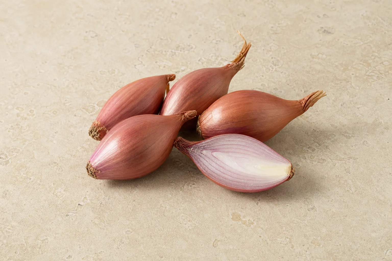 Small elongated copper-purple shallots with one cut half showing tight pale-purple layers.
