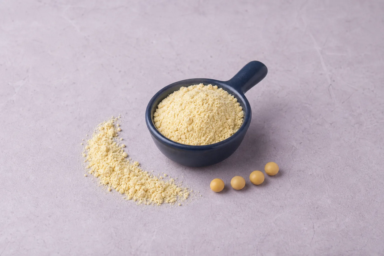 A navy scoop of pale cream-yellow flour with a short spill and several soybeans.
