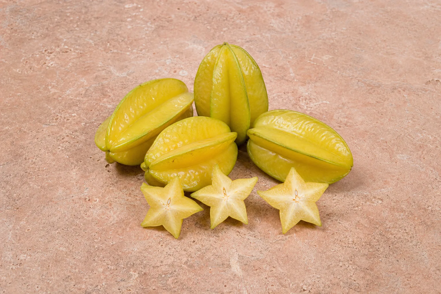 Yellow-green raw starfruit with three cross-cut star-shaped slices.