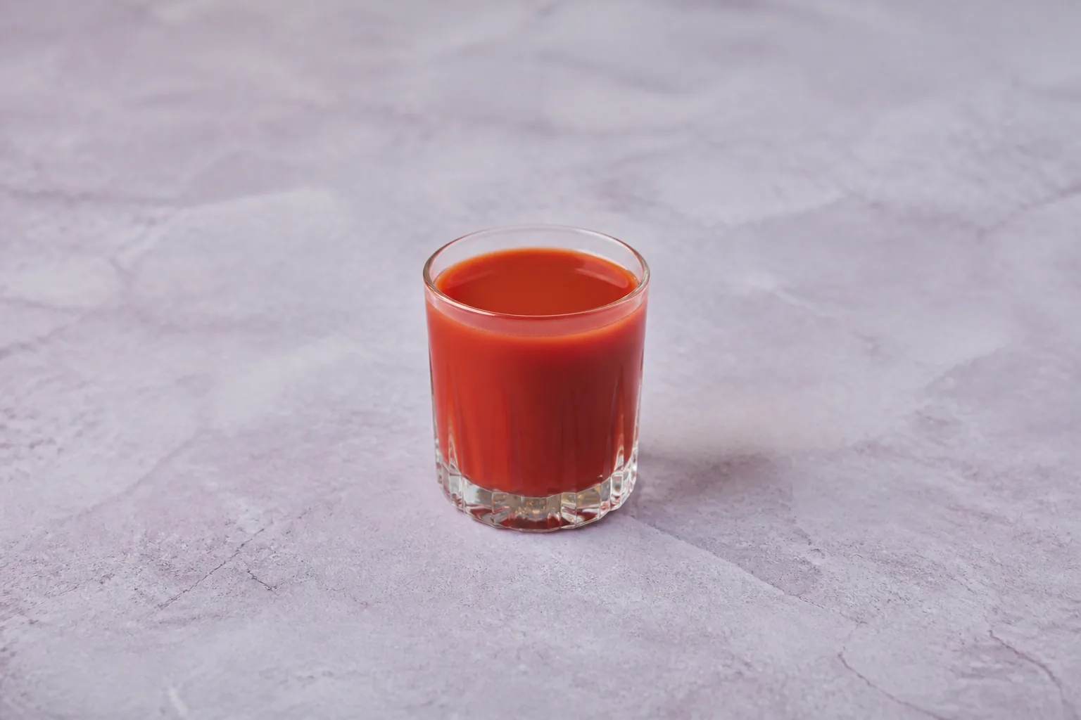 A clear glass filled with opaque muted red vegetable juice.