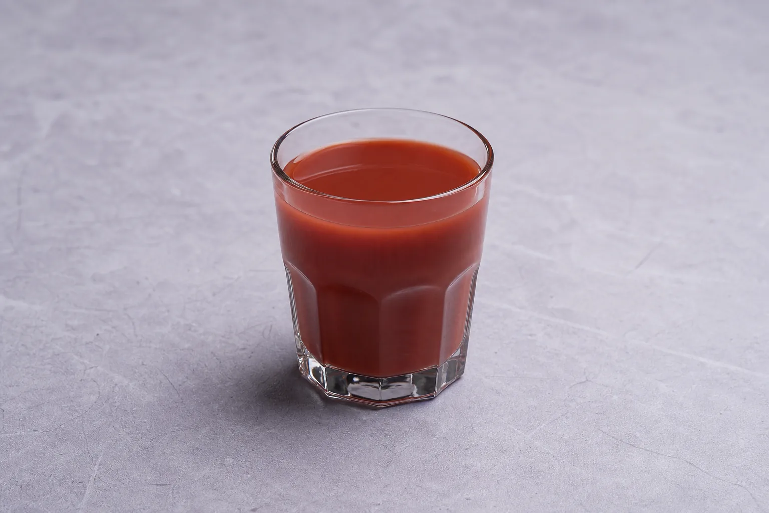 Opaque red vegetable juice cocktail in a clear faceted glass.